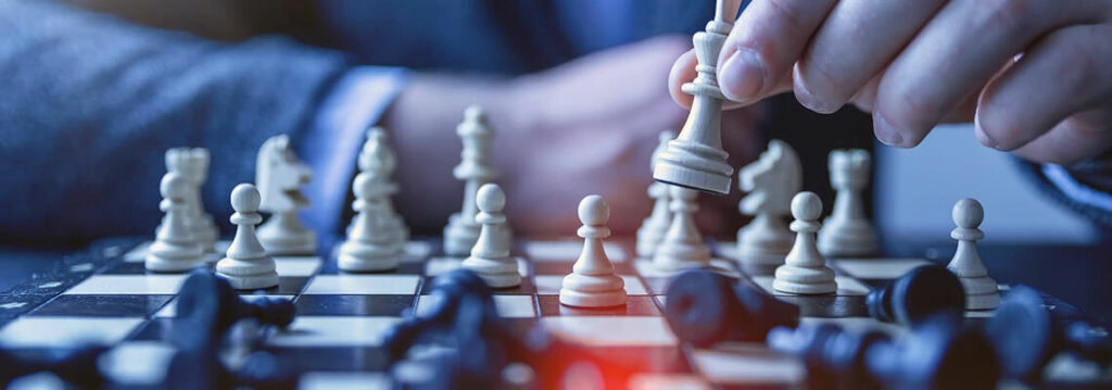 Checkmate position on a chessboard with a hand moving a white king piece. The scene emphasizes strategic gameplay and concentration during a chess match.